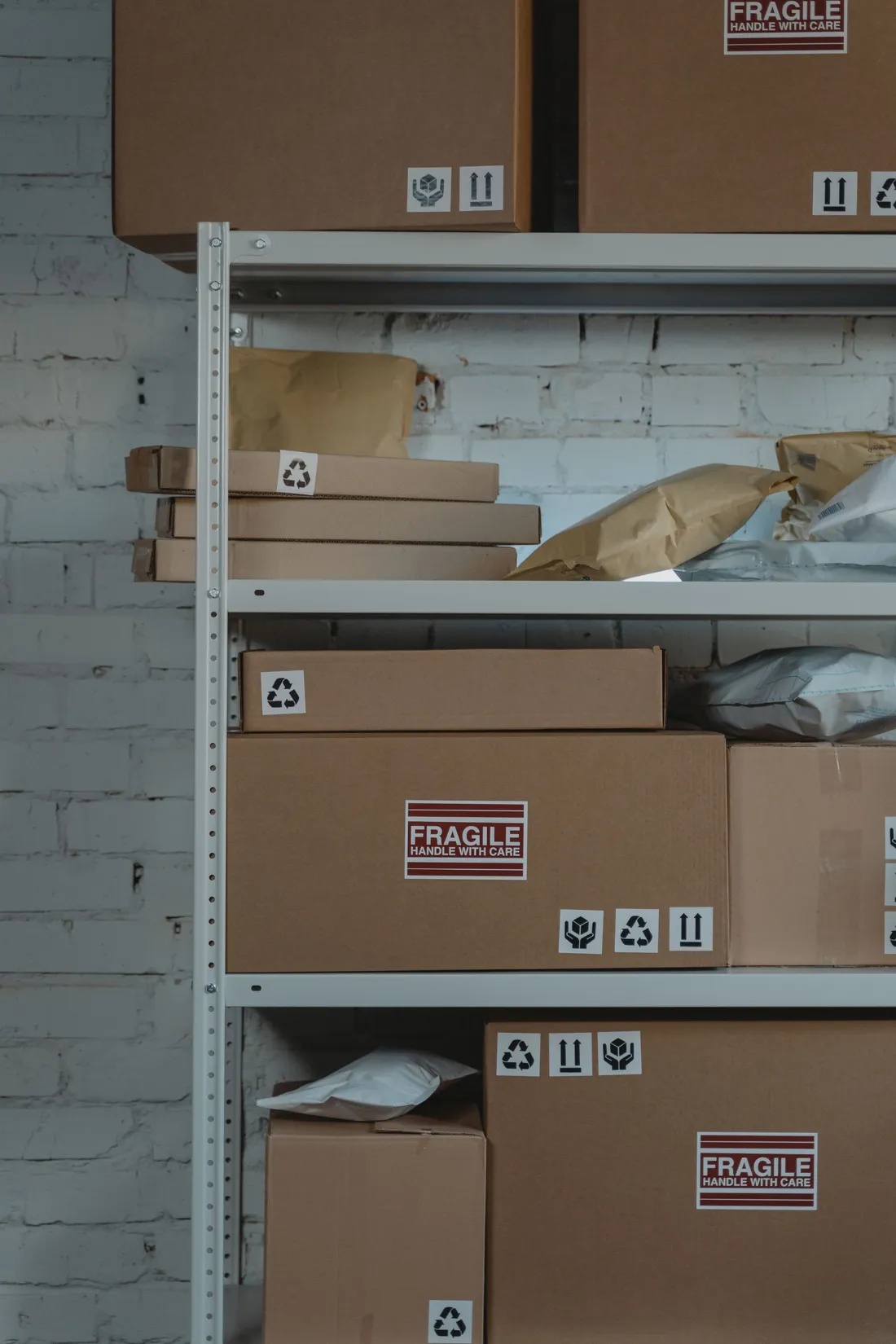 Labelled parcels and padded mailers stacked on back-room shelving